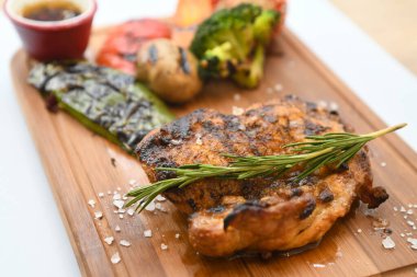 Biberiyeli ızgara tavuk budu ve ahşap tahtada kızartılmış sebzeler.