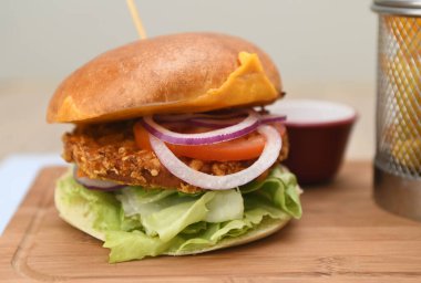 Marullu tavuk burger, soğan, çedar peyniri ve domates..