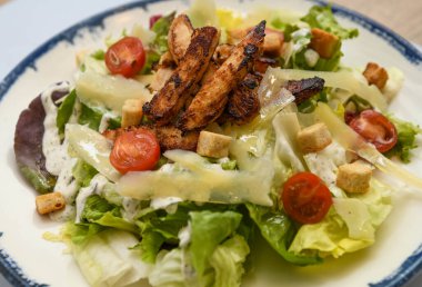 Kızarmış tavuk ve vişneli domatesli Sezar salatası, yakın plan.