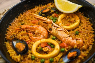 Ahşap bir masada deniz mahsullü İspanyol paella 'sı. Geleneksel İspanyolca yemek