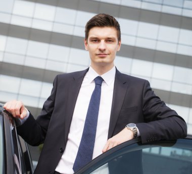 Yakışıklı genç iş adamı arabasının yakınındaki