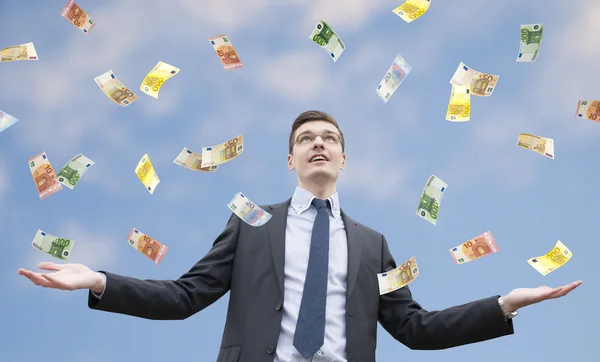 Feliz hombre de negocios parado bajo la lluvia de dinero Fotos de stock