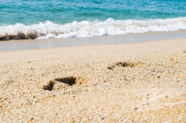 Kumsaldaki ayak izleri, arka planda deniz, sahil
