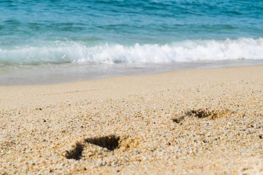 Kumsaldaki ayak izleri, arka planda deniz, sahil