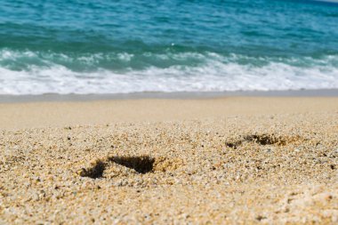 Kumsaldaki ayak izleri, arka planda deniz, sahil