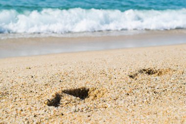 Kumsaldaki ayak izleri, arka planda deniz, sahil