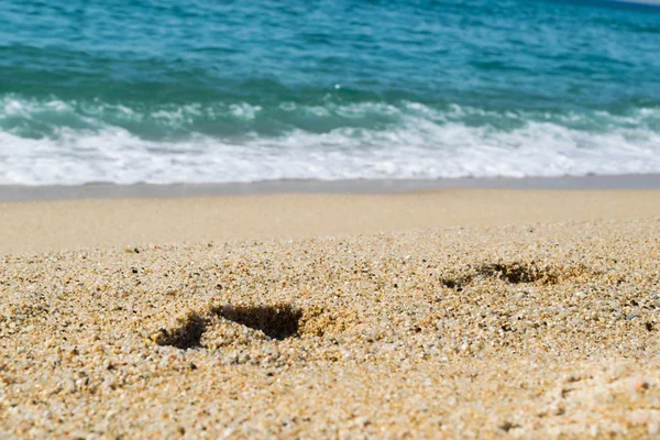 Kumsaldaki ayak izleri, arka planda deniz, sahil