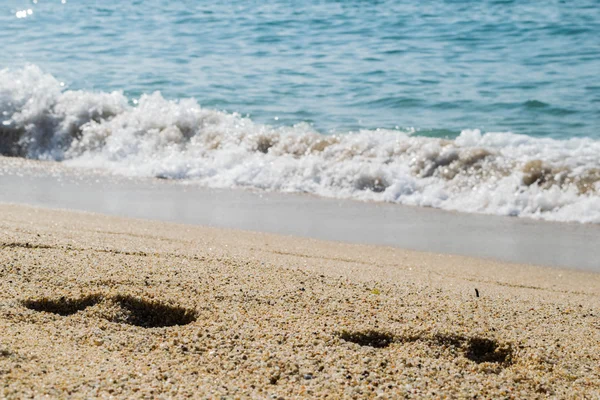 Kumsaldaki ayak izleri, arka planda deniz, sahil