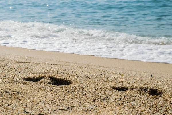 Kumsaldaki ayak izleri, arka planda deniz, sahil