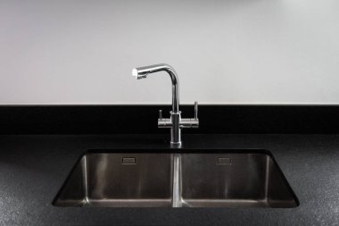 A double bowl stainless steel kitchen sink in a modern style, steel chrome water tap in the kitchen