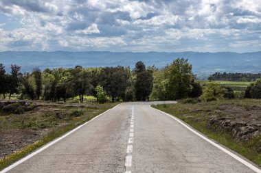 Güzel bulutlu gökyüzü, otoyol, Katalonya, İspanya 'nın altında yeşil çimenler arasında boş beton yol