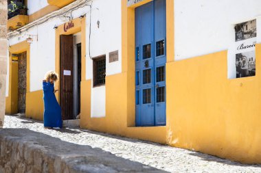 Mavili kadın İbiza 'nın eski kasabasında, mavi ve sarı renkler mimaride