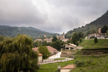 Vidra köyü yazın yeşil dağlarda, bulutlu gökyüzünde, yeşil eski şehir Vidra 'da kilise Katalonya, İspanya
