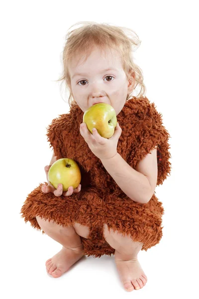 Piccolo divertente ragazzo di Neanderthal in un vestito con la faccia sporca mangiare una mela . — Foto Stock