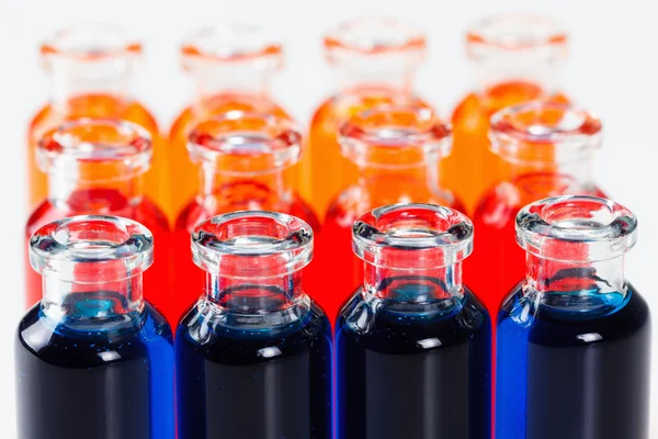 白い背景の上の化学研究室試験の試験管内青、赤、オレンジ色の液体 — ストック写真