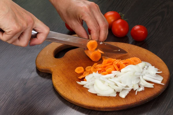Möhren und Zwiebeln auf einem Brett schneiden — Stockfoto