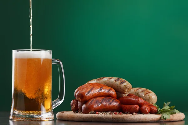 Kiełbaski z grilla ze szklanką piwa — Zdjęcie stockowe