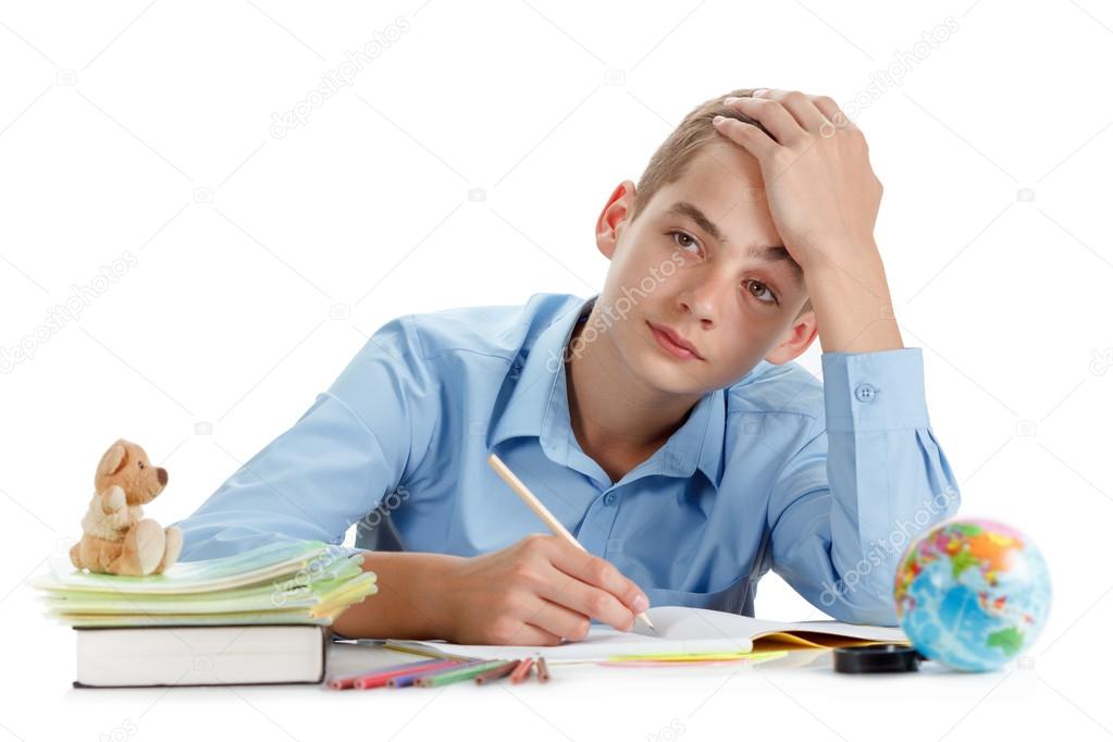 Boy sits near the desk with school supplies isolated on white background