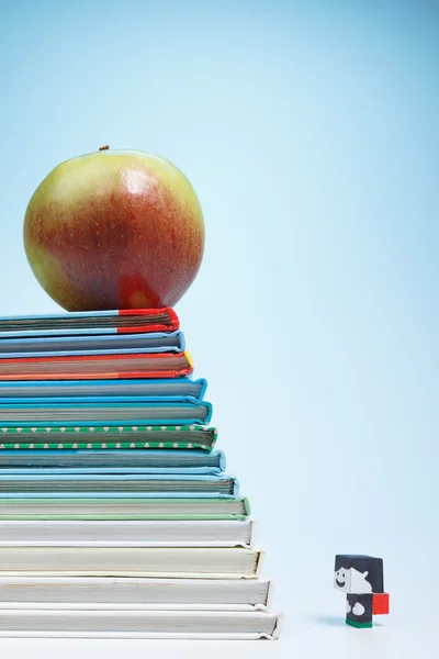 Muñeca escolar y una manzana en los libros —  Fotos de Stock