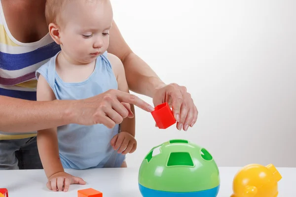 赤ちゃんと母親は青いドレスの笑顔でおもちゃで遊ぶ — ストック写真