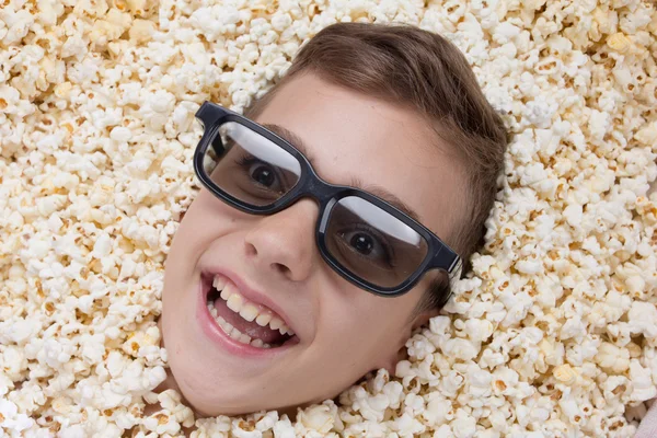 Laughing young boy in stereo glasses looking out of popcorn — Stock Photo, Image