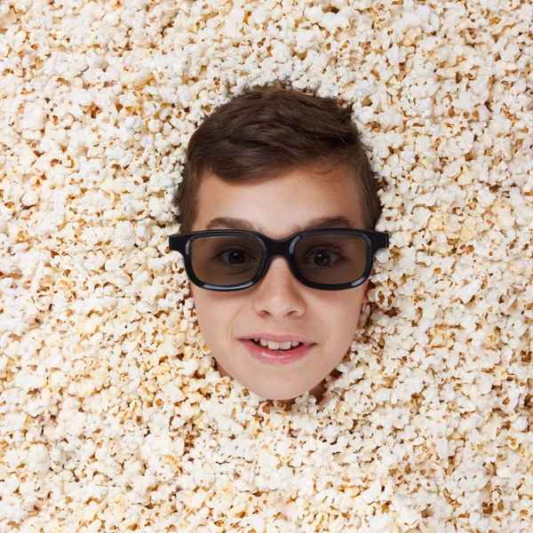 Sourire, exhiber jeune garçon dans des lunettes stéréo regardant hors de pop-corn — Photo