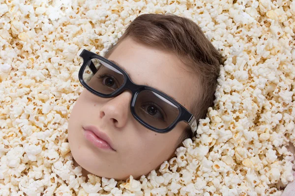 Sérieux jeune garçon dans stéréo lunettes regarder hors de pop-corn — Photo