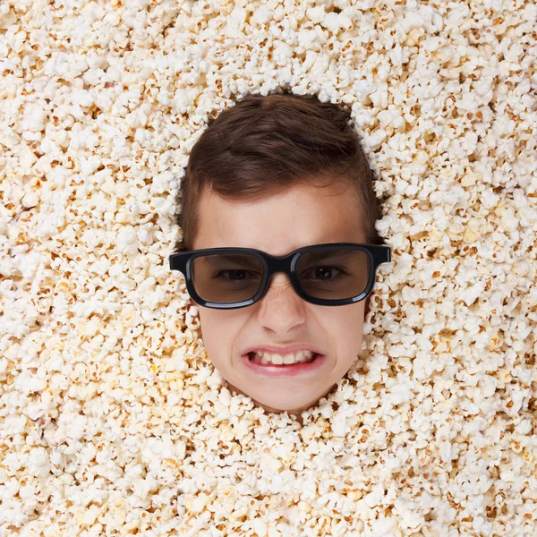 Böser wilder kleiner Junge in Stereogläsern schaut aus Popcorn — Stockfoto
