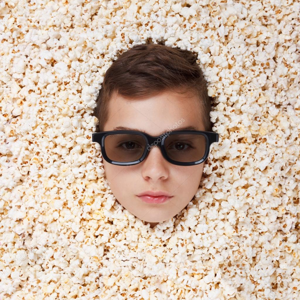 serious young boy in stereo glasses looking out of popcorn