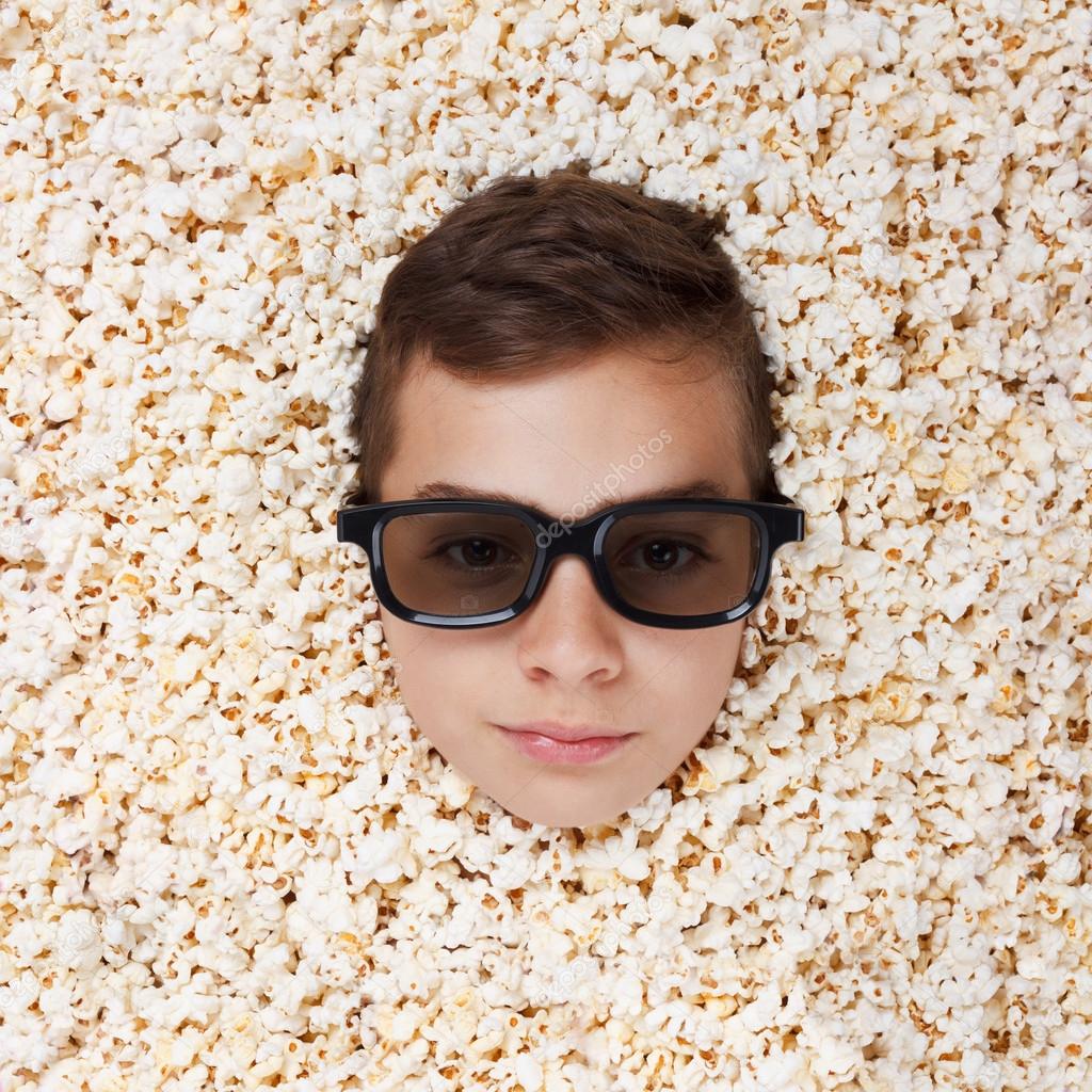 serious young boy in stereo glasses looking out of popcorn