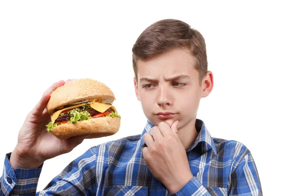 Jongen kijkt op een cheeseburger en denken. — Stockfoto