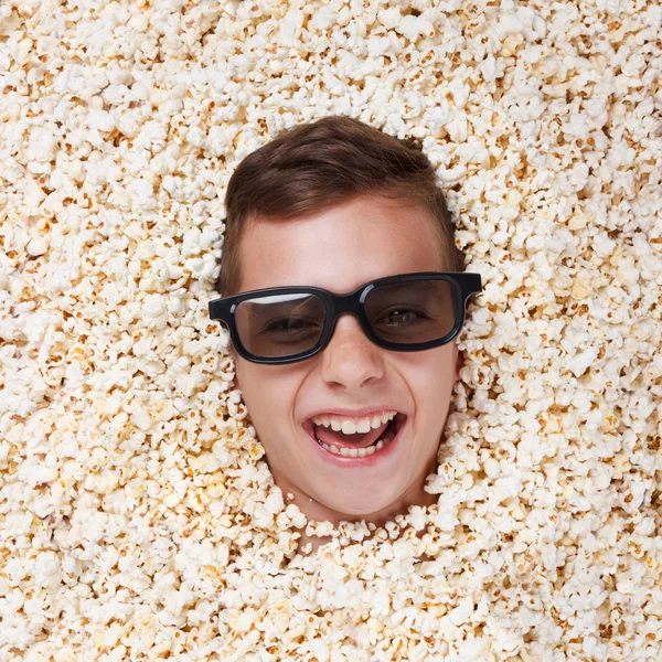 Rire jeune garçon dans des lunettes stéréo regardant hors de pop-corn — Photo