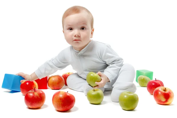 Baby spielt mit Äpfeln und Spielzeug. Studioporträt in halber Länge, isoliert auf weißem Hintergrund — Stockfoto