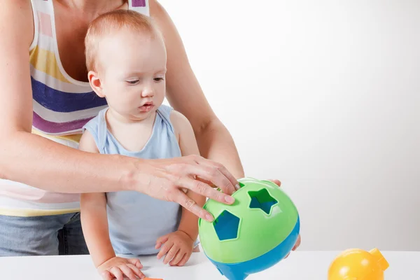 Mama bringt dem Baby bei, Spielzeug zu legen. Studiodreh — Stockfoto