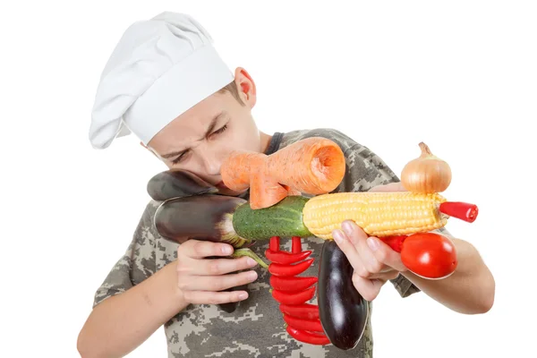 Portrait humoristique d'un chef adolescent avec des légumes fusil, fond blanc — Photo