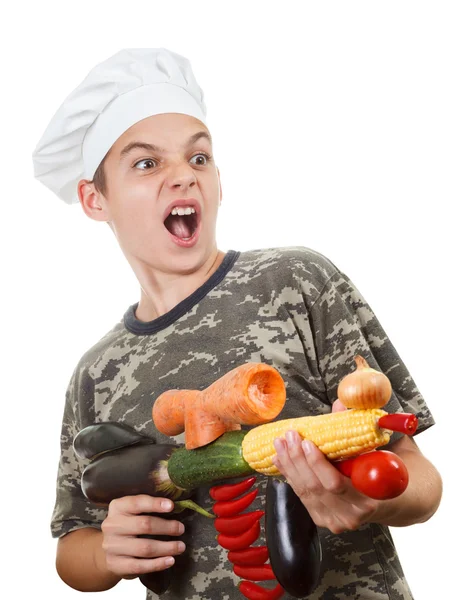 Humorous portrait of a teen boy chef with rifle vegetables, screaming cheers — Stock Photo, Image