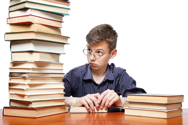 Здивований хлопчик дивиться на стос книг на білому тлі — стокове фото
