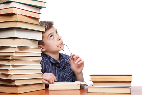 Niño reflexivo mirando hacia arriba y soñando con una pila de libros sobre fondo blanco —  Fotos de Stock