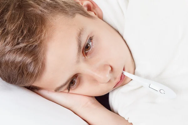 Teenager in bed with a thermometer. The temperature of the cold or flu. — Stock Photo, Image
