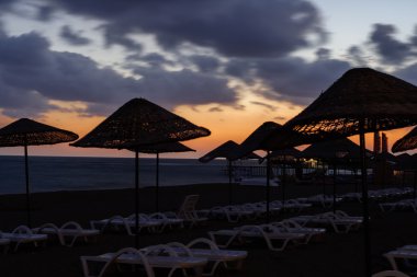 Deniz plaj şemsiye ve şezlong gün batımında