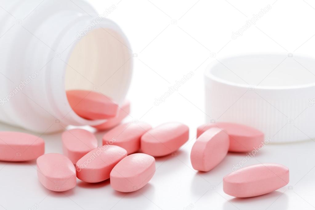 Pink oval pills poured out of a white bottle