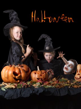 Cadılar Bayramı. İki küçük cadı, pumpkins, örümcekler ve bitki örtüsü ile çevrili kafatası