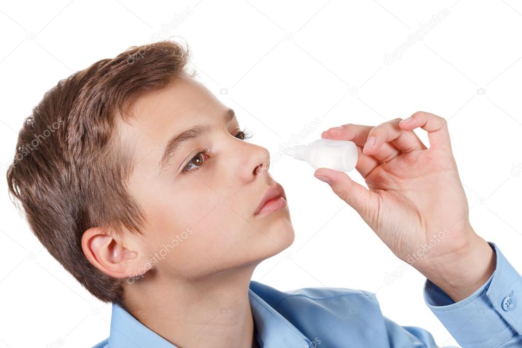 asal spray drops in hand of ill young boy, closeup on white