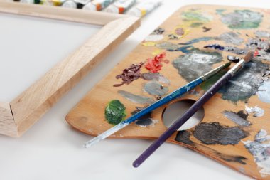 Boyalı sanat paleti ve beyaz arka planda fırça