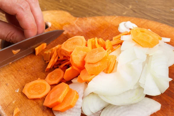 Masak memotong bawang dan wortel di atas papan potong — Stok Foto