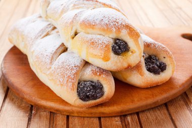 Ahşap arka plan üzerinde haşhaş tohumu ile ev yapımı hamur işleri