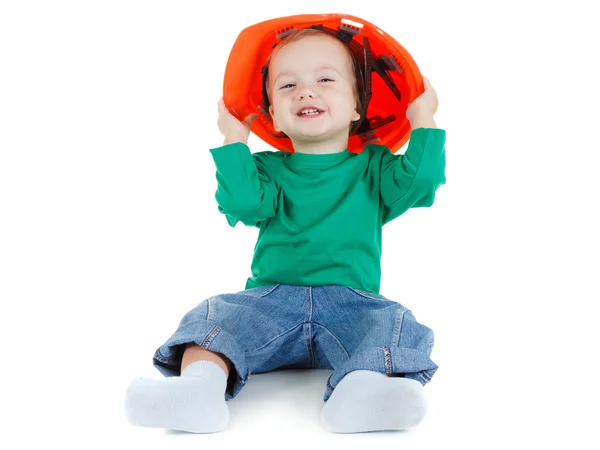Criança brinca com capacete protetor de construção laranja no fundo branco . — Fotografia de Stock
