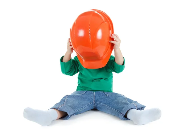 Little child plays with orange construction protective helmet  on white background. — Stock Photo, Image