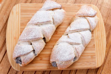 Ahşap arka plan üzerinde haşhaş tohumu ile ev yapımı hamur işleri