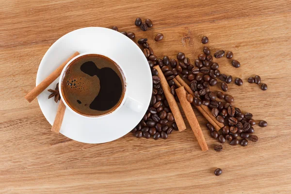 Coffee cup and beans, cinnamon sticks, anise on wooden table — Stock Photo, Image